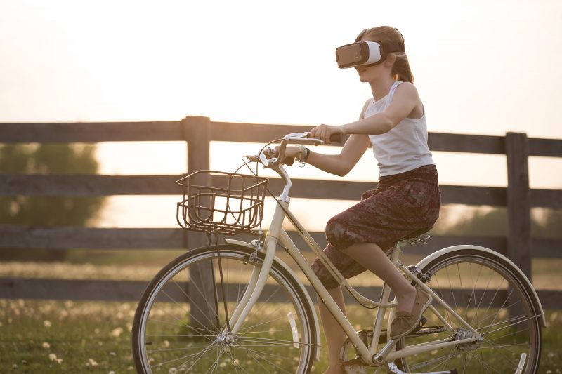 Girl riding bike in country side with a VR headset on